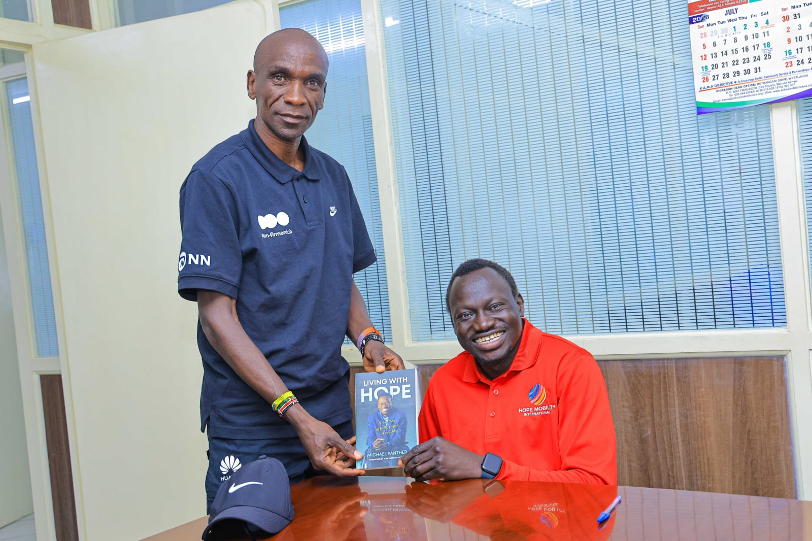Eliud Kipchoge standing alongside Michael Panther of Hope Mobility Kenya holding a racing wheelchair.